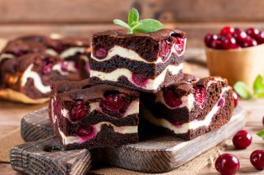Tasty chocolate brownie with cherry. Pieces of cake on rustic wooden table