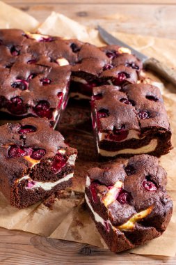 Brownie with cottage cheese and cherries on rustic wooden table