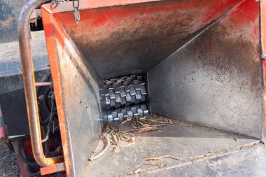 Arkaplanda odun öğütücünün alıcısına, römorka ve traktöre yakın çekim. Kullanılan ağaçların geri dönüşümü için toplama noktası.