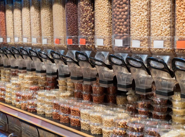 Dried nuts on the shelf at supermarket. Variety of seeds and nuts displayed in grocery store in reusable food dispensers. Shelf with glass jars full of dry food in organic shop. Grocery store interior.