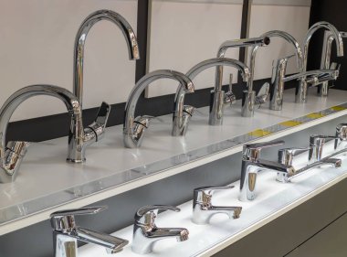 Satılık farklı banyo muslukları. Mutfak ve banyo için musluklu bir vitrin. Krom banyo muslukları. Özel bir ev eşyası mağazasında tesisat ticareti..