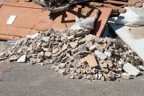 Construction waste. A pile of broken concrete debris and rubble. Demolition rubble. Junk, garbage piled up near the building. Street scene. Recycling industry, rubbish removal and collection service. Close-up.