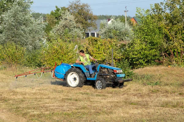 Male gardener on a Mini-tractor with motorized sprayer. Maintenance of the territory, sprays territory with insecticide for mosquitoes or pests or herbicides for weeds.