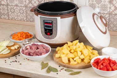 Modern, parlak, çoklu fırın ve mutfak masasındaki ürünler. Çoklu pişiriciyle haşlanmış patates pişirmek..