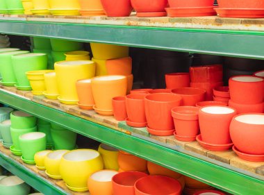 Bir mağazada ya da serada boş saksılar. Dükkandaki seramik ya da plastik saksılar. Mağazadaki raflarda renkli saksılar var. Bitkiler için renkli saksılar.