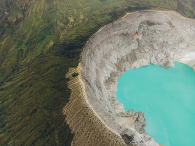 Doğu Java, Endonezya 'daki Kawah Ijen volkanında kayalıklarla çevrili turkuaz sülfür gölü üst hava manzarası..
