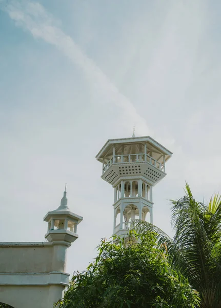 Stock image A beautiful elegant white tower with a palm tree, surrounded by a blue sky with clouds.