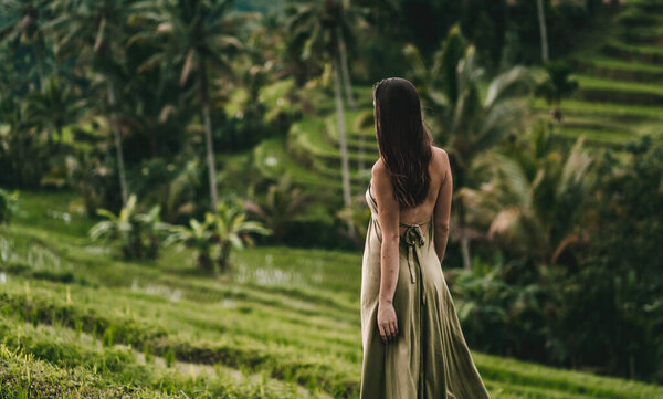 Back view of girl in green dress looking at rice terrace. Close up shot of elegant lady on a rice plantation