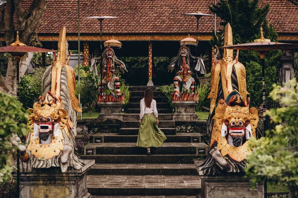 stock image Girl climbing stairs decorated with traditional barong statues. Balinese culture and decorative architecture