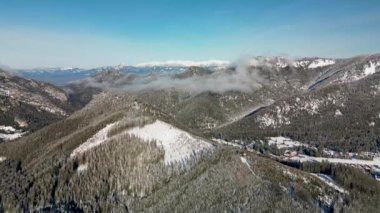 Slovakya 'nın Low Tatras dağlarındaki Demanovska Dolina köyünün Dolly hava panoramik kış manzarası. Kırsal kayalıkların karlı manzarası evler, donmuş çam ormanı ve yol manzarası
