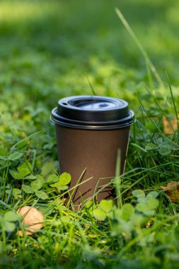 Kahverengi kağıt bardak ve sıcak kahvaltı kahvesi yaz aylarında yeşil çimenler şehir parkında ya da bahçede