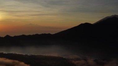 Sisli bir sabahta Batur Dağı panoramik manzara manzarası. Volkan Batur silueti sisli ve bulutlu gökyüzü