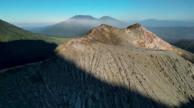 Sersemletici Ijen volkanik dağ manzarası bir krater kayası dağı, yemyeşil bitki örtüsü, bir vadi ve berrak mavi gökyüzü..