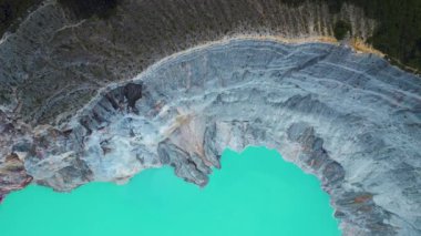 Doğu Java, Endonezya 'daki Kawah Ijen volkanında kayalıklarla çevrili turkuaz sülfür gölü üst hava manzarası..