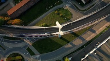 Polonya, Krakow 'daki tramvay hareketli asma köprü manzaralı İHA. Köprü yapısı ve toplu taşımacılık, boş asfalt yol ve aşağıdaki park günbatımı
