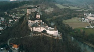 Oravsky Hrad 'ın hava aracı bakış açısı, Slovakya' ya seyahat. Ortaçağ aristokratlarının ünlü kalesi yüksek dağlarda, gece ormanlarında ve bulutlu günbatımı gökyüzünde manzara.