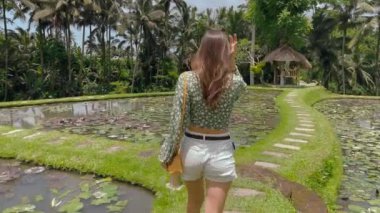 Orman bitkilerinde güzel bir bayanın arka görüntüsü. Genç kız tropikal doğanın güzelliklerini keşfediyor.