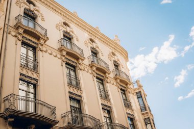 Valencia 'daki zarif tarihi bir binanın alçak açılı görüntüsü. Süslü balkonları ve detaylı mimari unsurları var. Temiz bir gökyüzü altında İspanyol mirasının güzelliğini yansıtıyor..