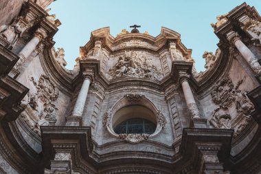 Valencia Katedrali 'nin süslü görünüşü, karmaşık oymalar ve mimari detaylarla dolu. Tarihi yapı berrak bir gökyüzüne karşı duruyor, ihtişamını sergiliyor..