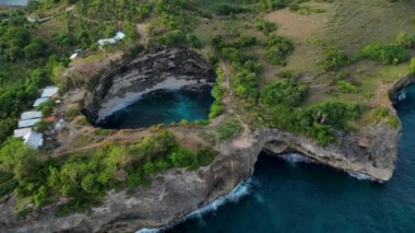 Bali 'nin Nusa Penida kentindeki kayalık uçurumlar ve yemyeşil yeşilliklerle çevrili berrak mavi sularla çevrili dairesel Kırık Sahil Koyu' nun havadan görüntüsü. İnzivaya çekilmiş körfez büyüleyici bir doğal geri çekilme sunuyor..