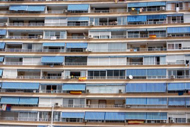 İspanya, Alicante 'de, güneşle parlayan, açık bir günde balkonları kaplayan mavi çizgili tenteleri olan bir yerleşim yeri..