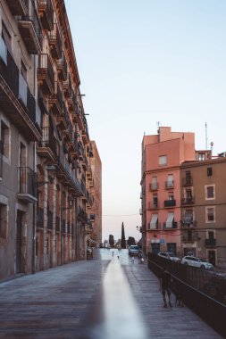 Tarragona, İspanya 'da akşam ışığının yumuşak parıltısıyla aydınlanan tarihi mimarinin yer aldığı çarpıcı bir şehir caddesi.