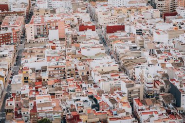 Sokaklar, çatılar ve eski konut binalarının karışımından oluşan kentsel yerleşim alanının havadan görünüşü kalabalık bir ortamda şehir yaşamını resmediyor..