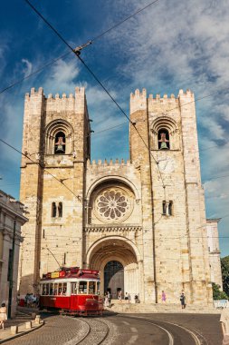 Tarihi Lizbon Katedrali, tipik bir kırmızı tramvay geçerken canlı şehir atmosferini yakalıyor. Lizbon, Portekiz - 11 Haziran 2025