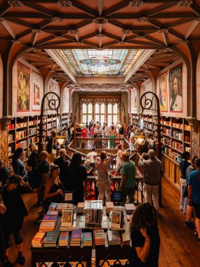 Turistler, kitaplarla ve canlı vitray tavanla dolu mimari açıdan göz kamaştırıcı ünlü bir kitapçıyı keşfediyorlar. Porto, Portekiz - 11 Haziran 2025