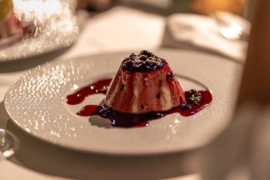 Çeşit çeşit böğürtlen ve lezzetli böğürtlen sosuyla süslenmiş panna cotta tatlısının tadını çıkarın.