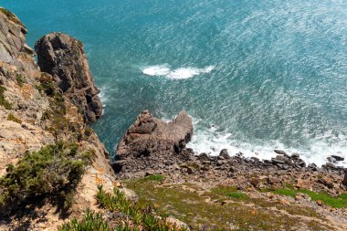 Dik kayalıklar, Lizbon bölgesinde doğa, seyahat ve macera temaları için mükemmel olan canlı turkuaz Atlantik Okyanusu ile buluşuyor. Manzaradan ilham almak için ideal..