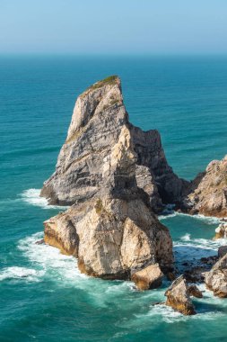 Portekiz, Lizbon yakınlarındaki Praia da Ursa 'daki turkuaz Atlantik sularından çarpıcı bir deniz yığını yükseliyor. Seyahat, doğa, macera ve kıyı manzarası için mükemmel..