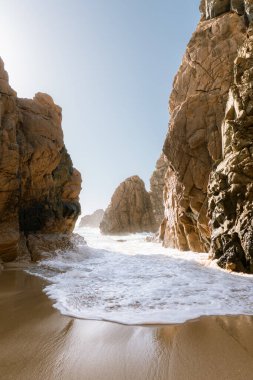 Gözlerden uzak bir sahile vuran okyanus dalgalarının çarpıcı görüntüsü. Etrafı yüksek kayalıklarla çevrili. Lizbon bölgesinde seyahat, doğa ve macera için mükemmel bir ilham kaynağı..
