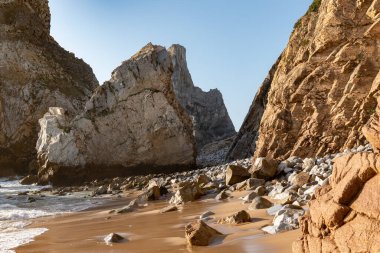Lizbon, Portekiz yakınlarındaki Praia da Ursa 'nın çarpıcı manzarası dramatik kaya oluşumları, altın kum ve açık mavi gökyüzü seyahat, doğa ve macera ilhamı için mükemmel..