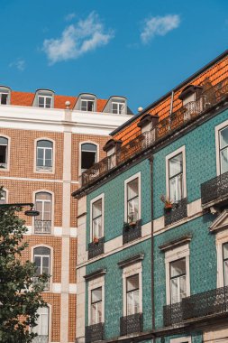 Vibrant Lisbon buildings with iconic azulejo tiles and red rooftops under a clear blue sky, perfect for travel blogs, architecture features, and Portugal tourism content.