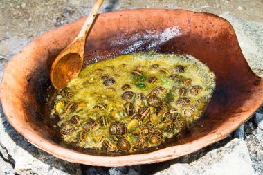 Minoan mutfağının leziz yiyecekleri. Girit 'in kırsal kesimindeki bir orman yangınında kil tenceresinde salyangoz pişirmek..