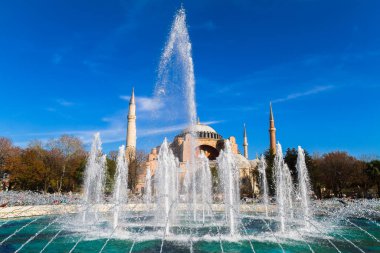 Mavi gökyüzündeki çeşme. Arka planda İstanbul Türkiye 'deki Ayşe Sofya Holly Wisdom bazilikası görülüyor. Kilise olarak inşa edildi, daha sonra bir camiye dönüştürüldü ve şimdi bir müze..