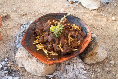 Mediterranean cuisine ancient delicasy foods. Cooking rabbit stew in a clay cookware pot over a wood fire in rural central Crete. clipart