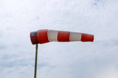 Mavi gökyüzüne karşı büyük kırmızı beyaz çizgili bir rüzgarlık.