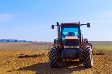 A large tractor stands on the field. Modern large machinery in the field. Shadow from a tractor on the ground.
