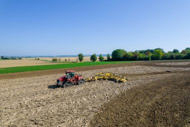 Büyük bir traktörle çiftliği harap ediyor. Arazide tarım işi. Yukarıdan görüntüle.