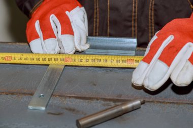 Markings on metal surface for drilling holes. Worker uses a tool to measure and mark on an iron surface.