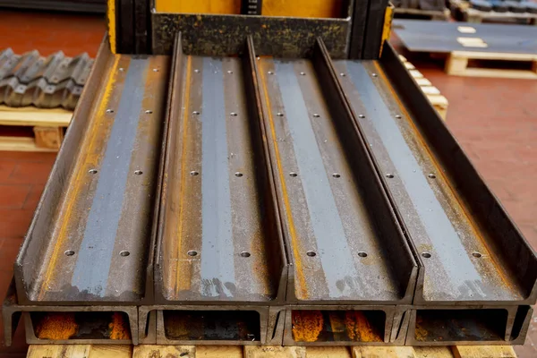 A stack of rolled metal cut to a given length with drilled holes is on the pallet. Various products from a metal of a channel.