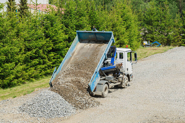 На строительной площадке произошла выгрузка гравия из самосвала.