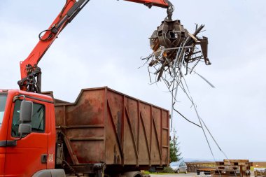 Hurda metali bir kamyona yüklüyorum. Turna yakalayıcısı rıhtımdaki paslı hurdaları yüklüyor. Yakalayıcı bir kamyon geri dönüşüm için endüstriyel metali yüklüyor.