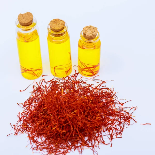 stock image A pile of dry saffron stamens and a serving of saffron drink in cans on a white background. Infused tea from dry saffron stamens.