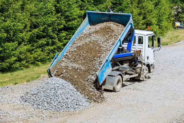 On the construction site, a dump truck is dumping gravel that has been loaded into it.