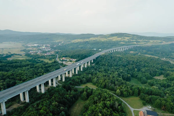 Dağlık bölgede, yol ve ağaçlarda ulaşım köprüsü. Doğanın yukarıdan panoramik görüntüsü.