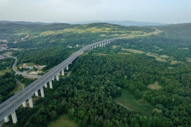 Dağlık bölgede, yol ve ağaçlarda ulaşım köprüsü. Doğanın yukarıdan panoramik görüntüsü.