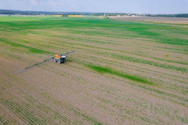 Püskürtücülü bir traktör alanı gübreyle işliyor. Tahıl mahsullerini zararlılardan korumak. Yeşil alanın işlenmesi.